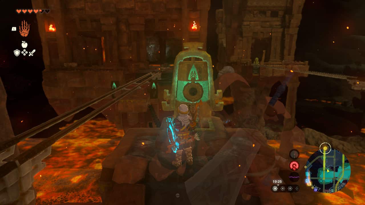 Tears of the Kingdom Fire Temple: Link next to a bell-shaped switch with minecart tracks on the left leading to a building.