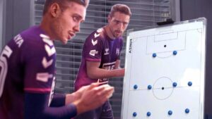 5 changes FM25 needs to make: Two players applauding next to a whiteboard with a football formation marked out on it.