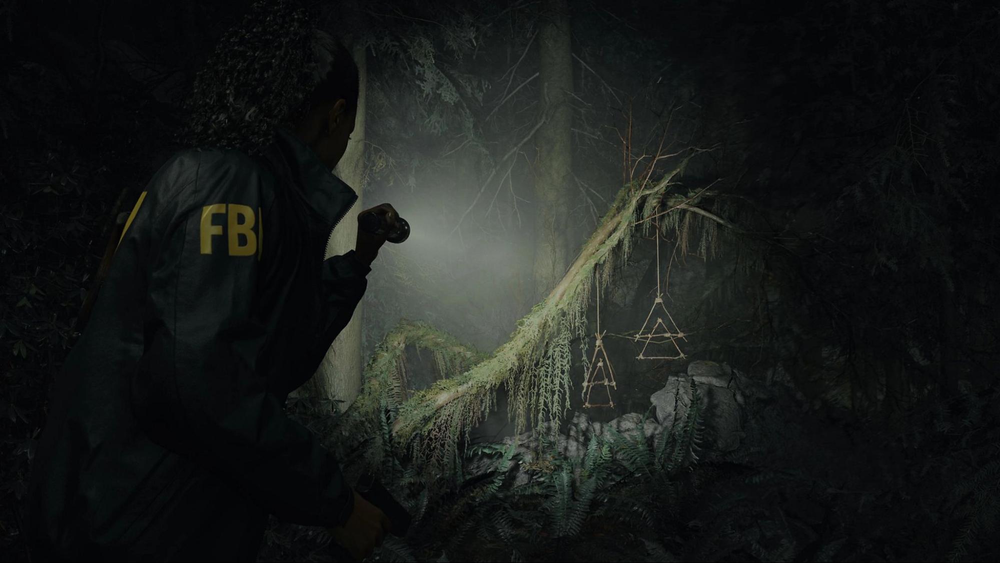Alan Wake II gameplay with FBI agent Saga Anderson searching a dark forest with flashlight, investigating supernatural events.