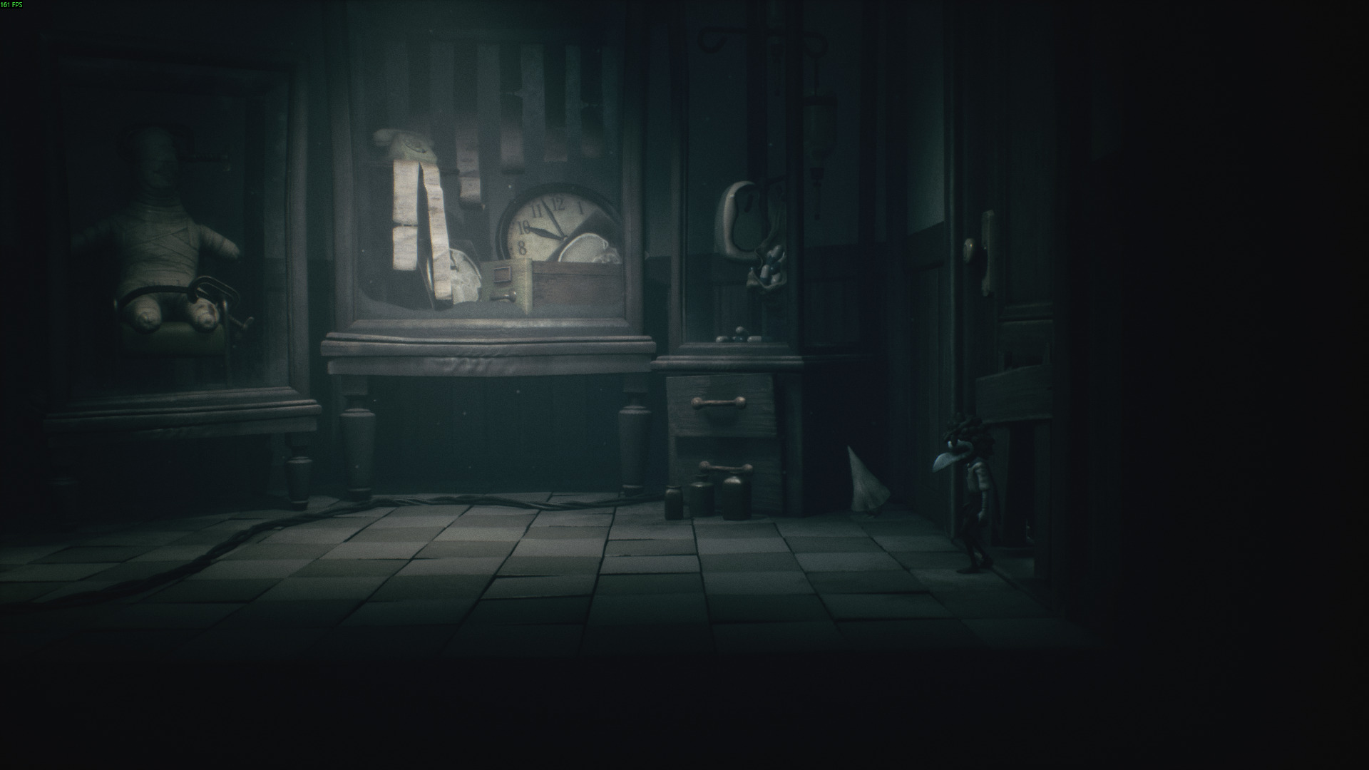 Two small characters stand in a creepy room in Little Nightmares 3, with a bandaged doll and a broken clock on display