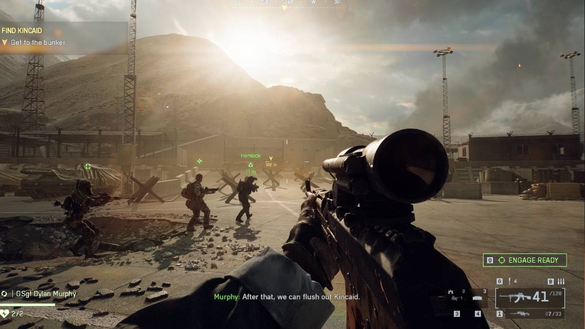 A group of soldiers advances toward a mountain bunker in Battlefield 6, with the player aiming through a scoped rifle under the setting sun.