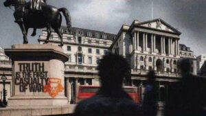 Silhouettes of people walk by a statue of a horse and rider, with graffiti on the statue's base reading "Truth is the first casualty of war," reminiscent of themes explored in Black Ops 6, all set against the backdrop of a neoclassical building.