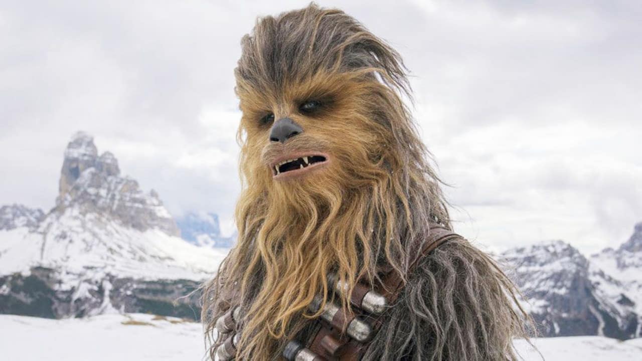 Chewbacca, a Wookiee character from Star Wars, stands in front of snowy mountain peaks reminiscent of Fortnite landscapes.