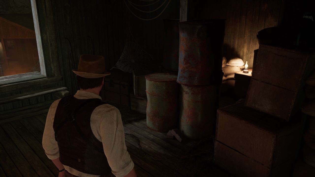 A character in a fedora and suspenders examines a dimly lit room filled with barrels and crates, experiencing the eerie lagniappe of Alone in the Dark.