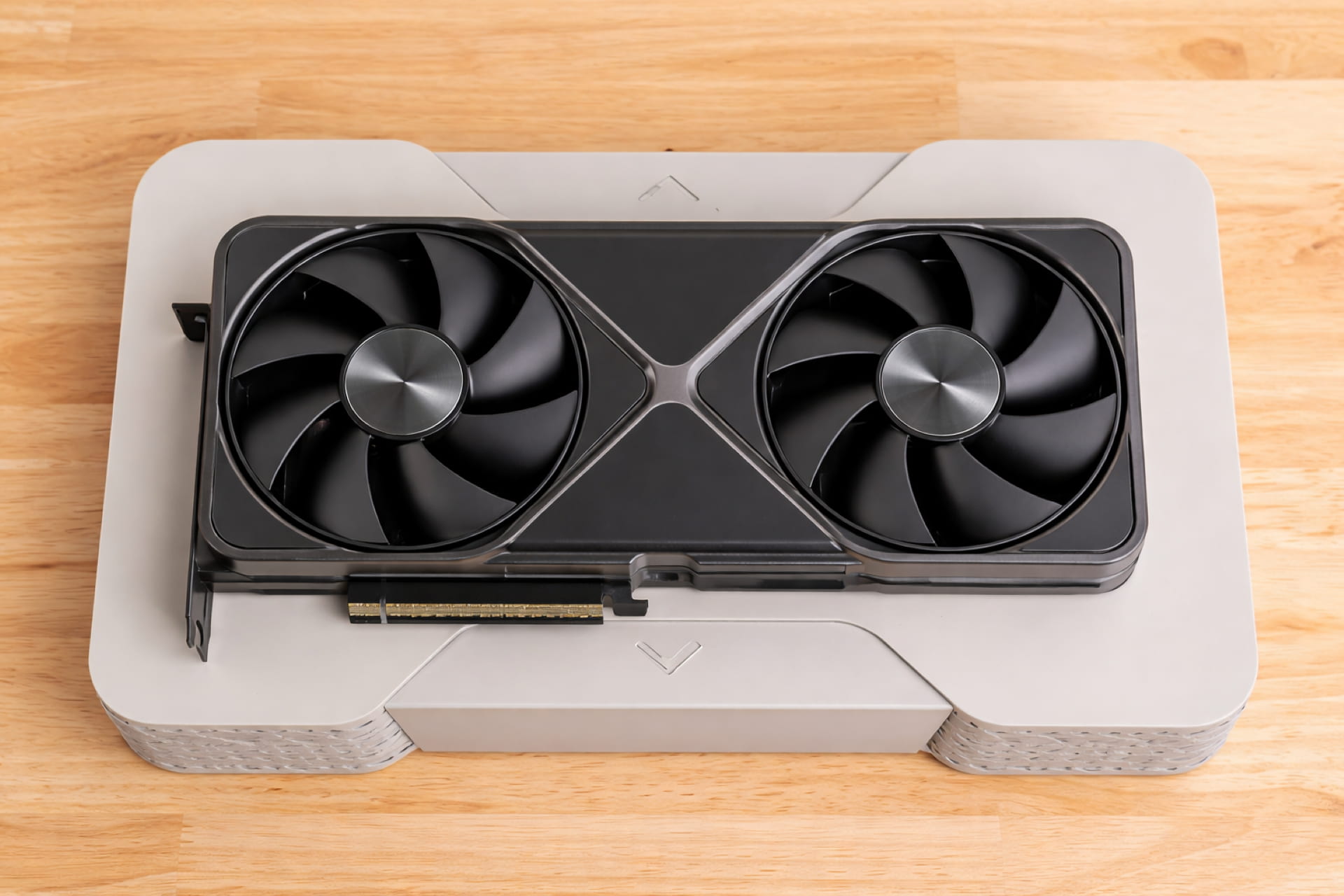 Top-down view of a sleek dual-fan graphics card resting on a light wood surface, presented as game ready driver compatible hardware.