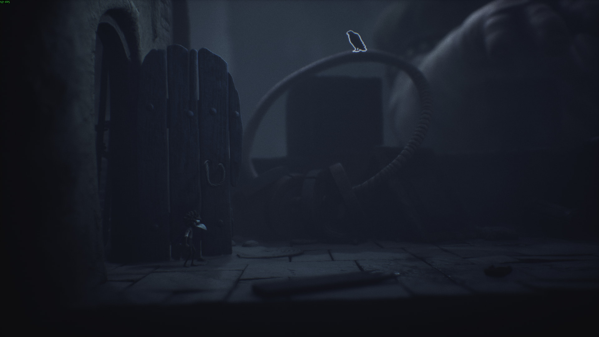 A crow sits atop a metal ring near a doorway in Little Nightmares 3
