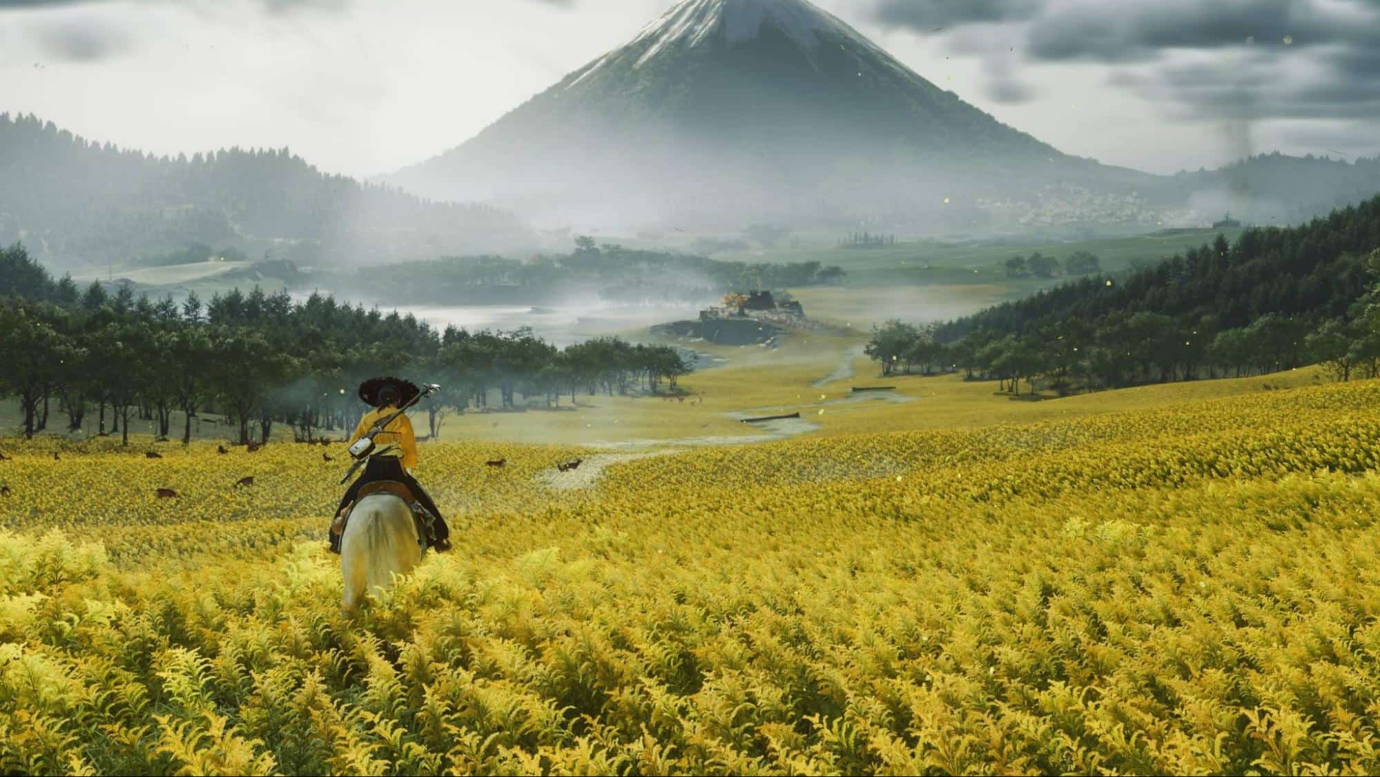 Character riding a horse through a vast yellow field with a snow-capped mountain in the background in Ghost of Yotei
