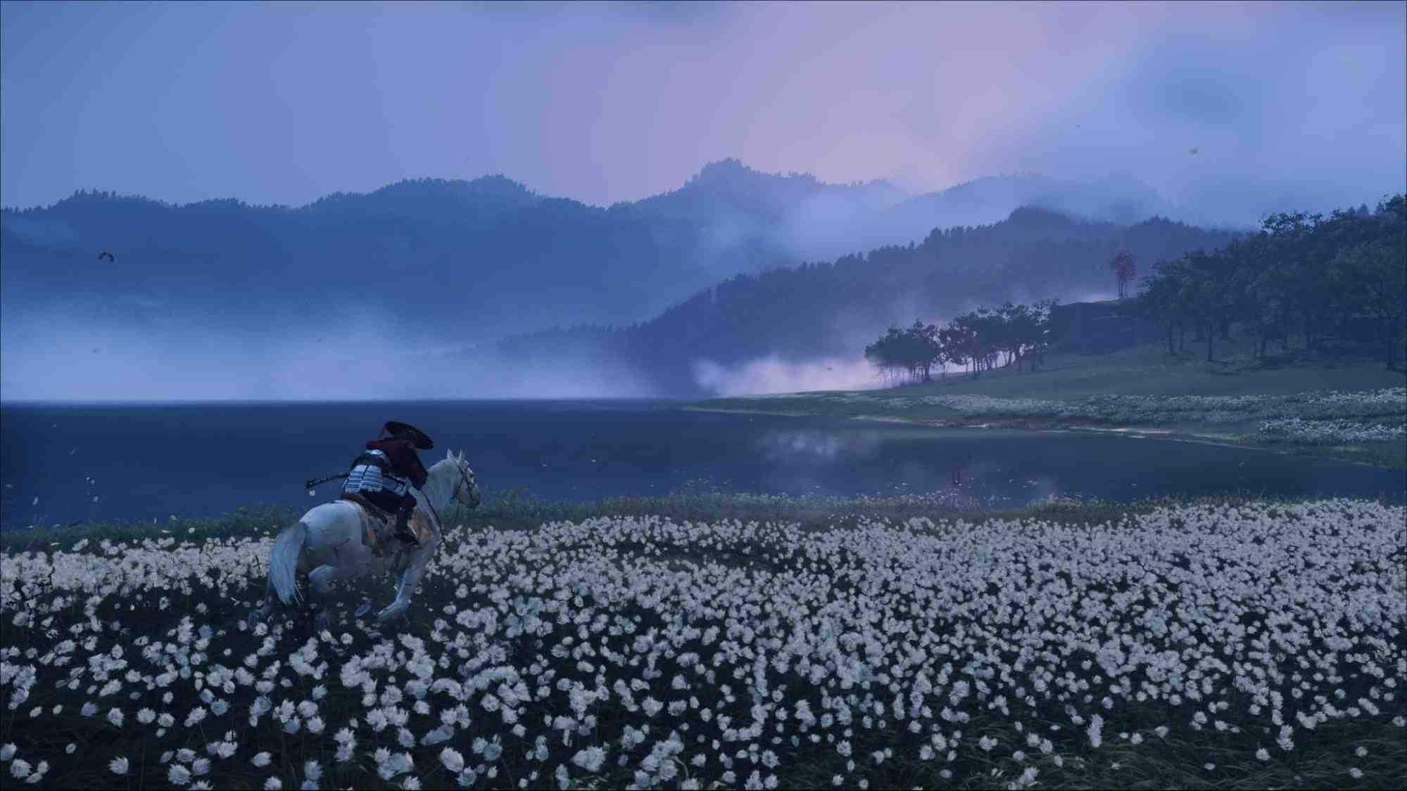 Atsu riding a white horse through a large field of white flowers near a misty blue lake in Ghost of Yotei, with mountains in the background.
