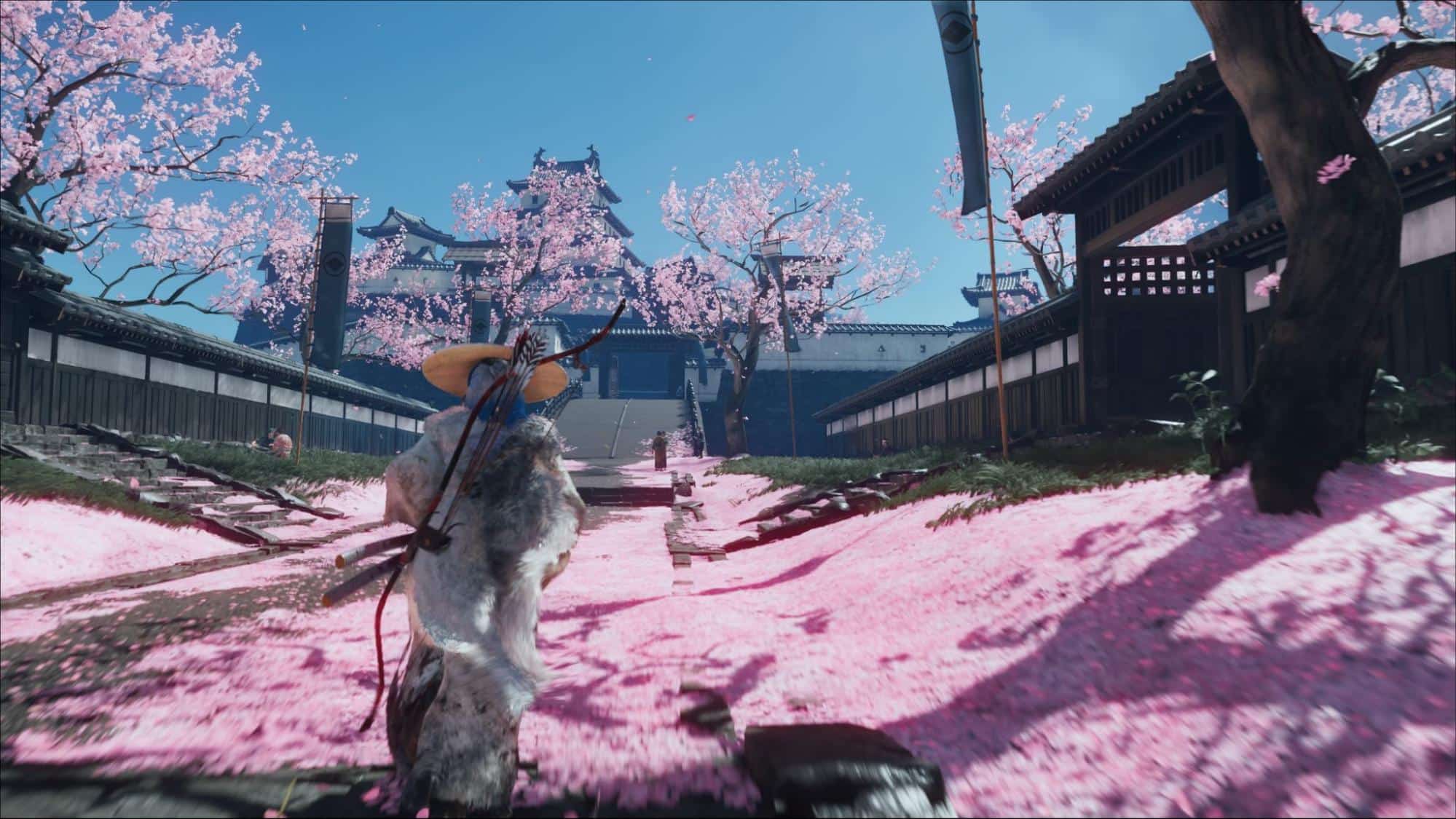 Warrior walks toward a castle lined with cherry blossoms in Ghost of Yotei