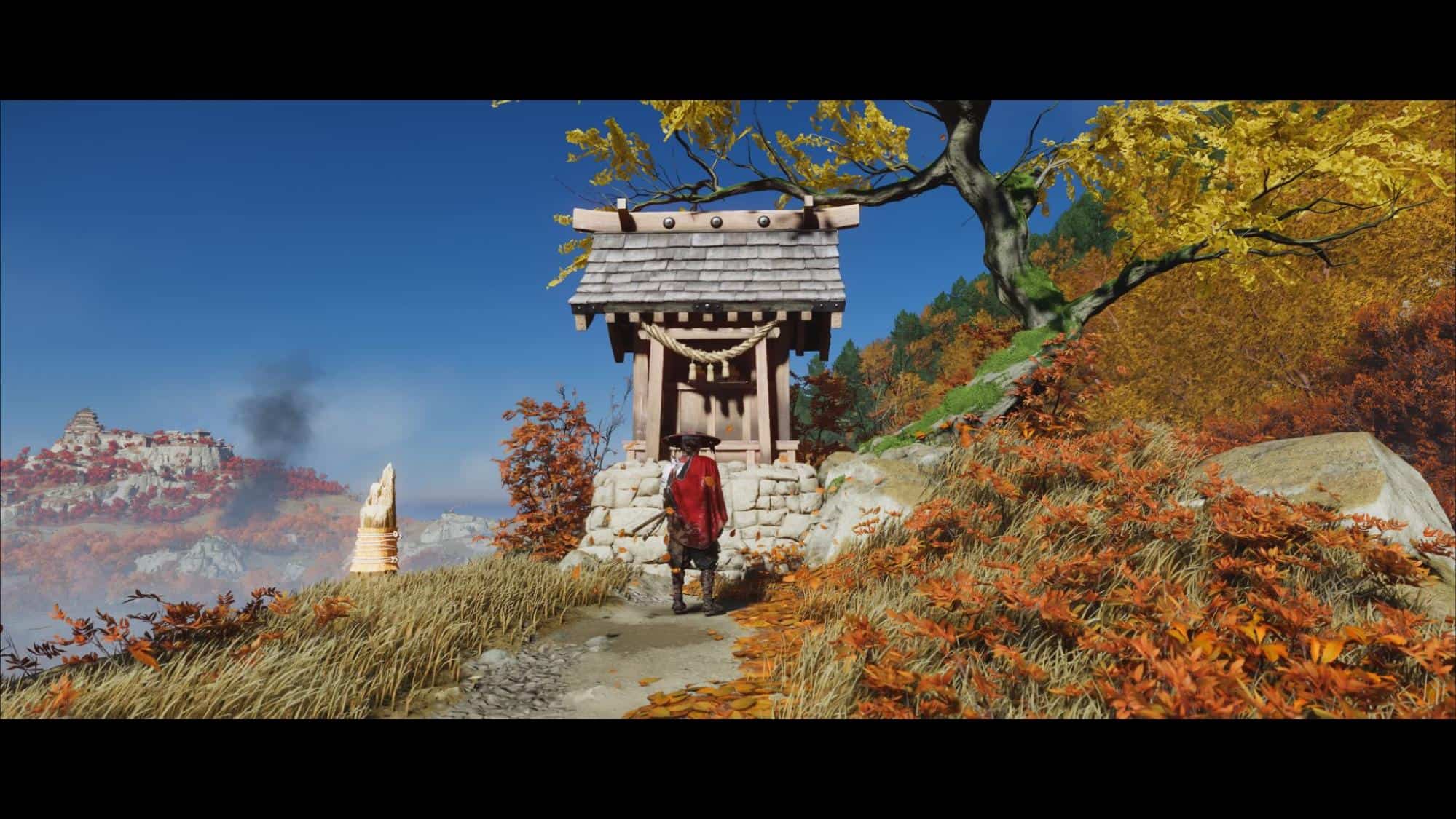 Warrior stands before a small shrine in autumn hills in Ghost of Yotei