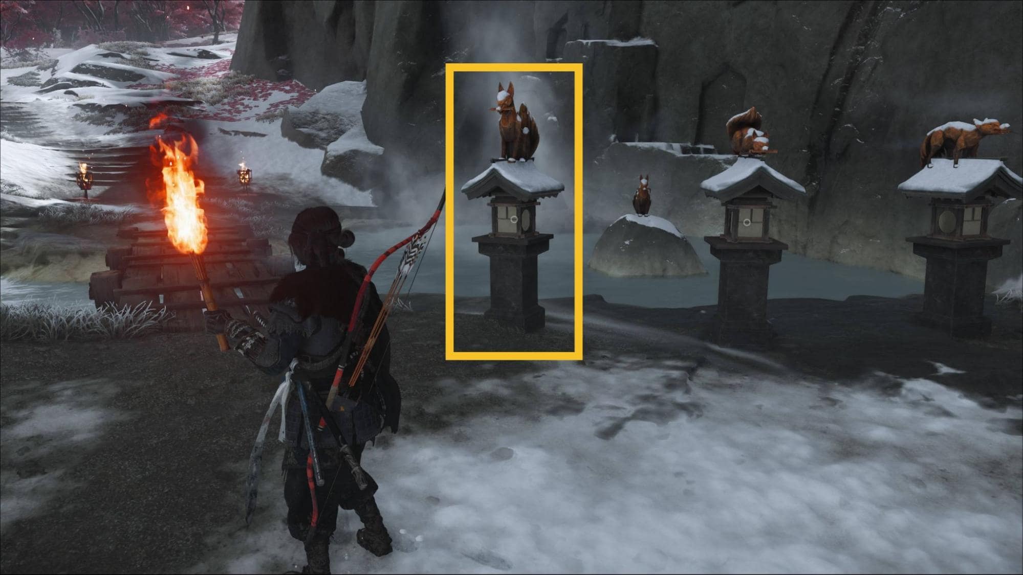 Player holds a torch near fox lanterns by a frozen pond at the Ghost of Yotei Snow Drift Springs Shrine, with the correct one marked in yellow