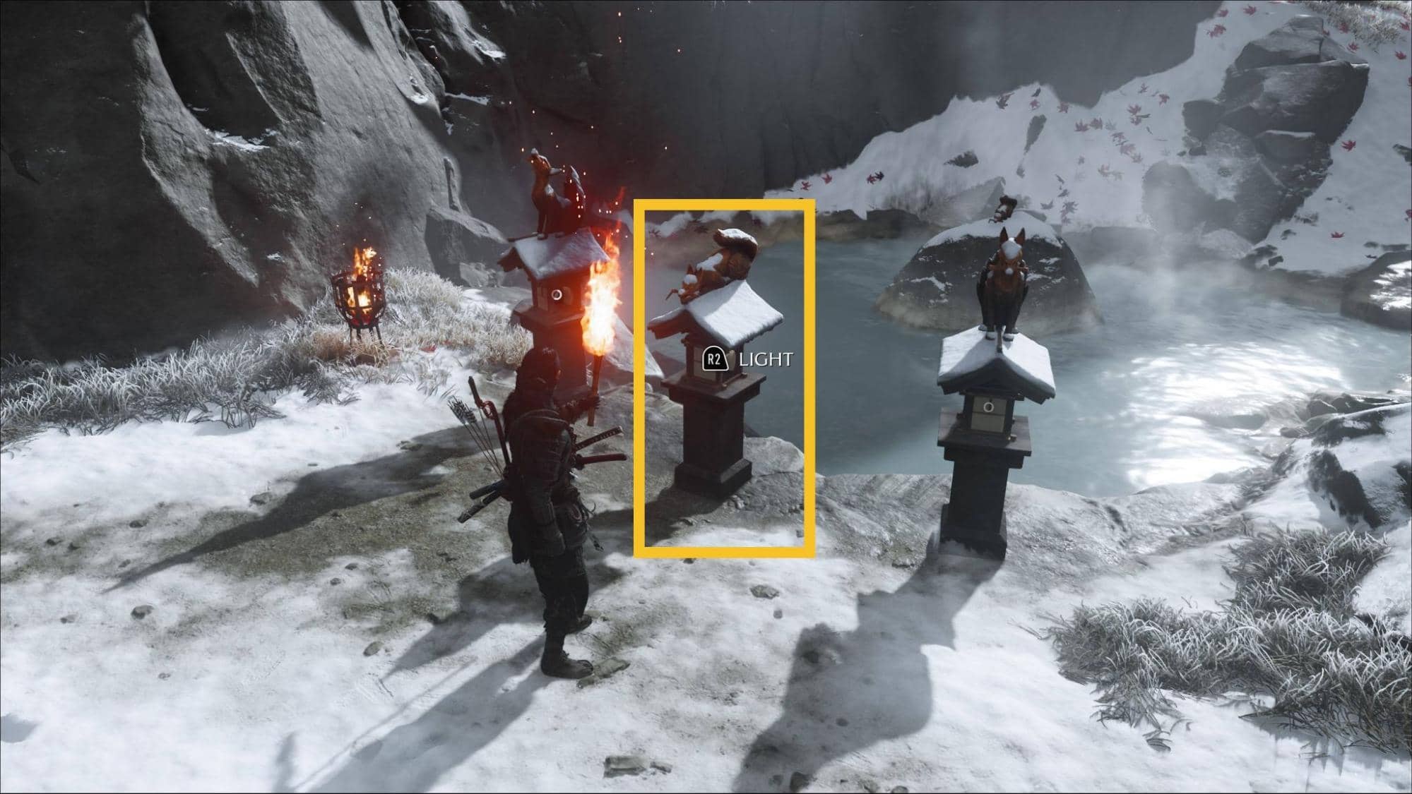 Player prepares to light the correct fox lantern marked in yellow beside a frozen pond at the Ghost of Yotei Snow Drift Springs Shrine