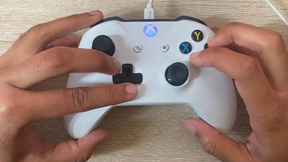 A person's hands are holding a white Xbox One controller while playing Mortal Kombat with the best controller settings.