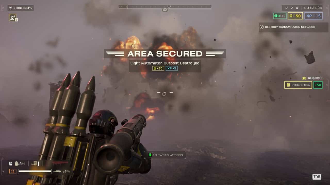 First-person view in a video game with an airburst rocket launcher in the foreground, looking at an explosion at a distant outpost, with text "area secured" displayed.