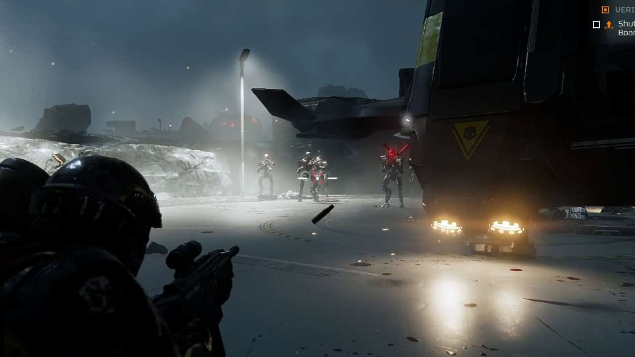First-person view of a Helldivers 2 soldier aiming a gun at enemies in armored suits near a crashed aircraft at night.