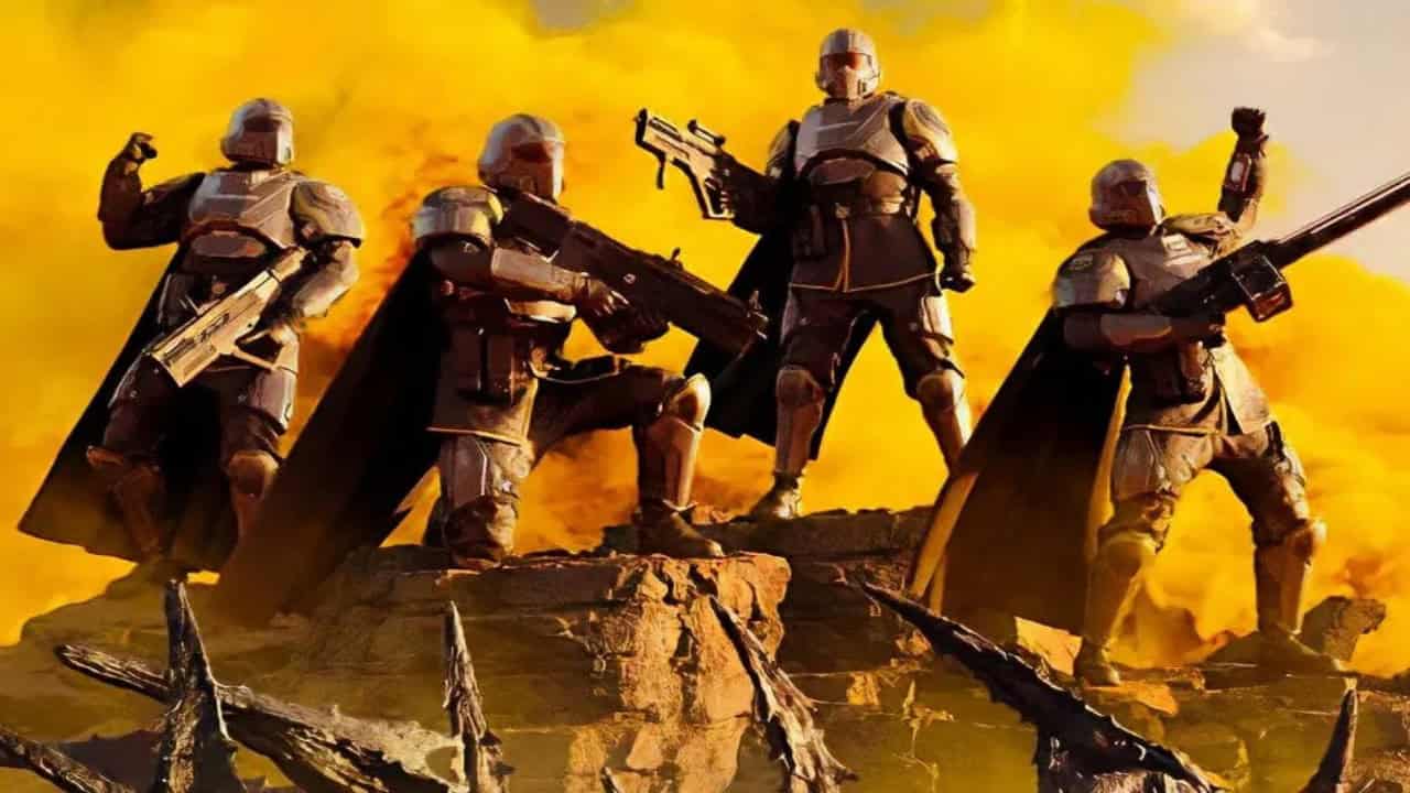 Four futuristic soldiers in armor stand on rocky terrain against a fiery yellow sky, one holding a large gun, as "Helldivers 2" takes over the real world.