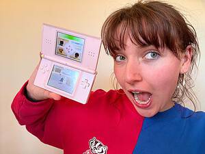 A woman holding up a pink Nintendo DS, showcasing Nintendogs
