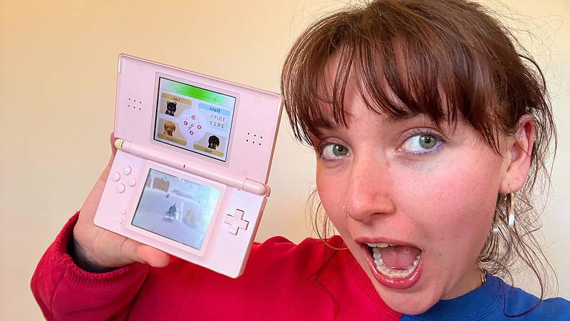 A woman holding up a pink Nintendo DS, showcasing Nintendogs