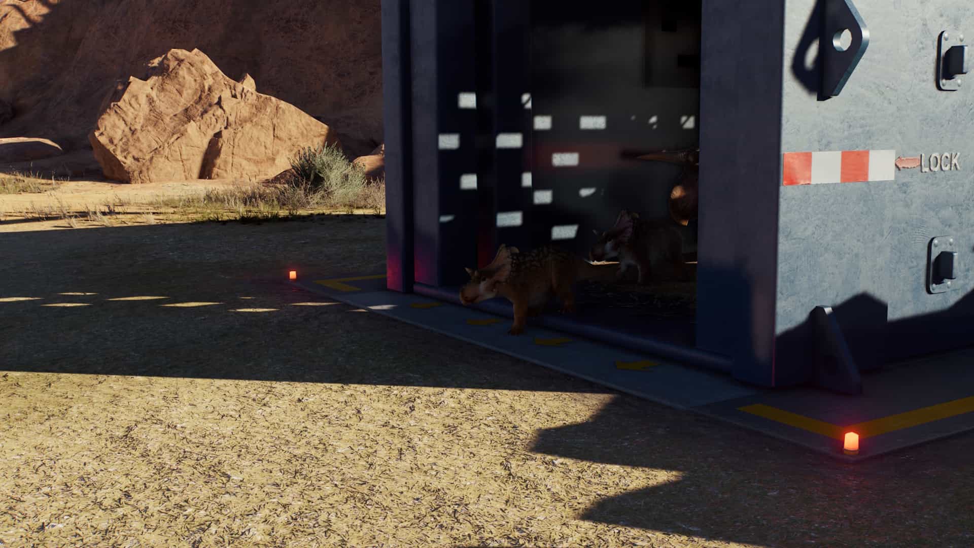 Two small dinosaurs step out of a transport crate into a desert enclosure in Jurassic World Evolution 3.