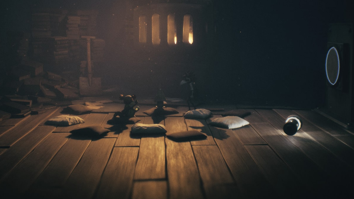 Small characters gather near a glowing furnace in Little Nightmares 3, surrounded by scattered pillows and a fallen flashlight