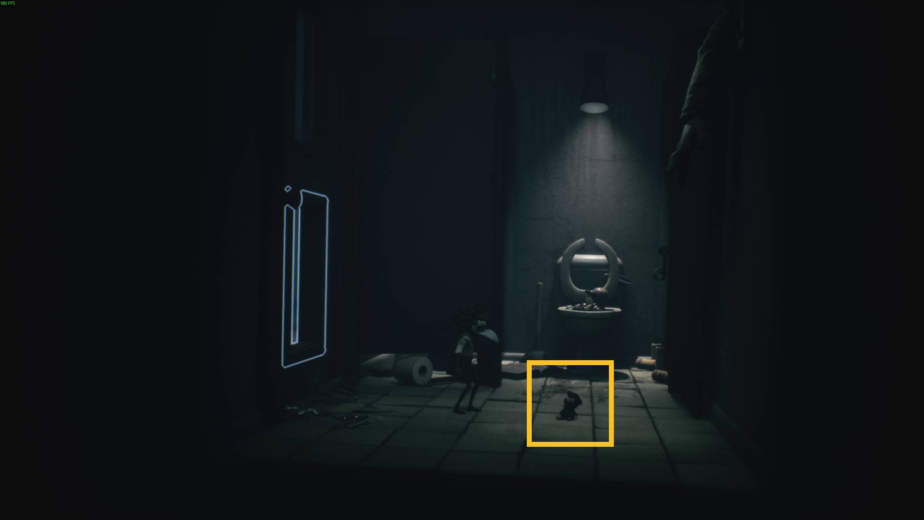 A small doll-like figure on the bathroom floor near a broken toilet, with a child character standing close by in Little Nightmares 3.