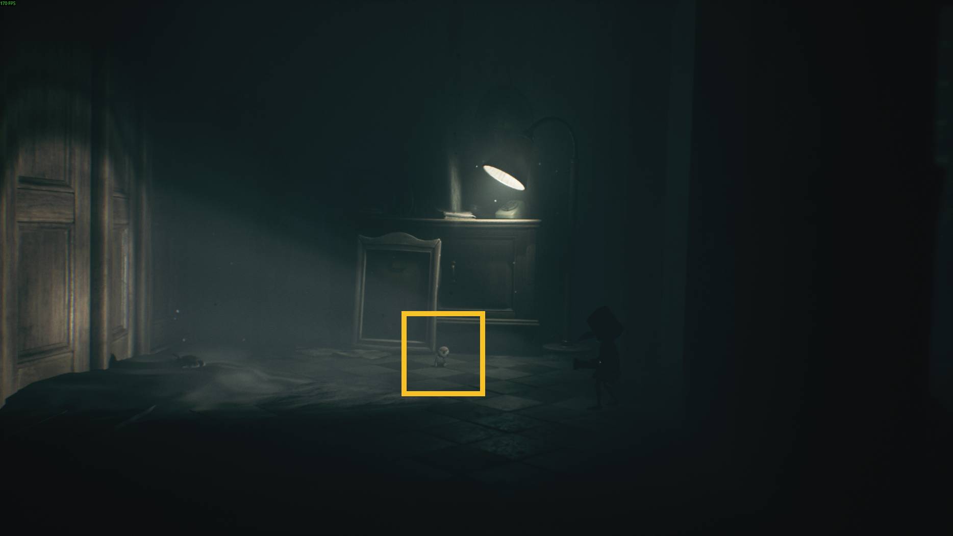 A small doll sits under a glowing lamp in a dimly lit room in Little Nightmares 3