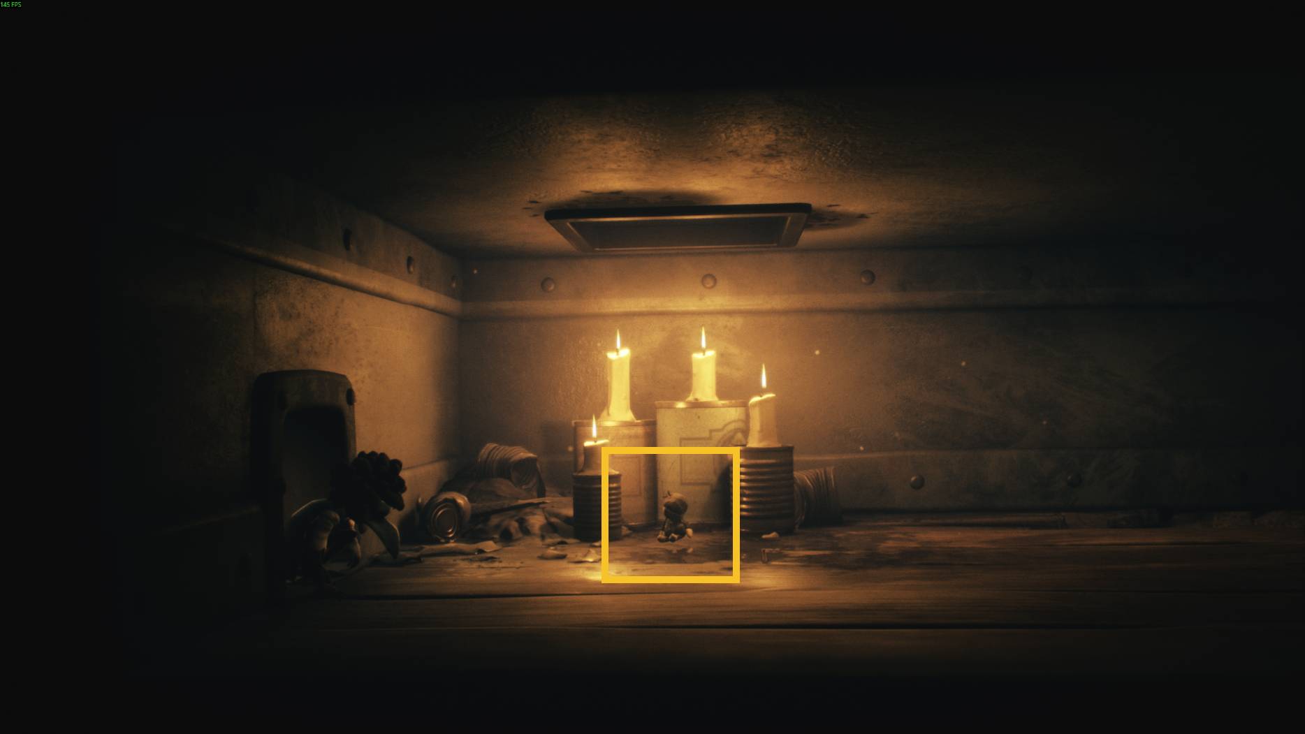 A doll-like figure surrounded by burning candles in a dimly lit corner, creating an eerie scene in Little Nightmares 3