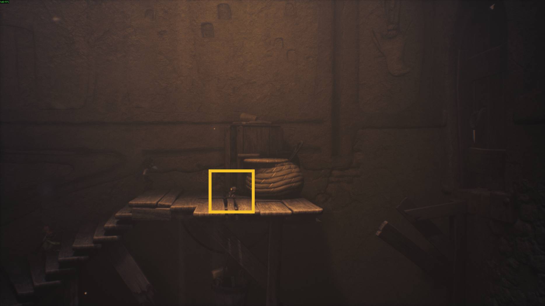 A small character stands on a fragile wooden platform in Little Nightmares 3, beside a large basket and a sealed door.