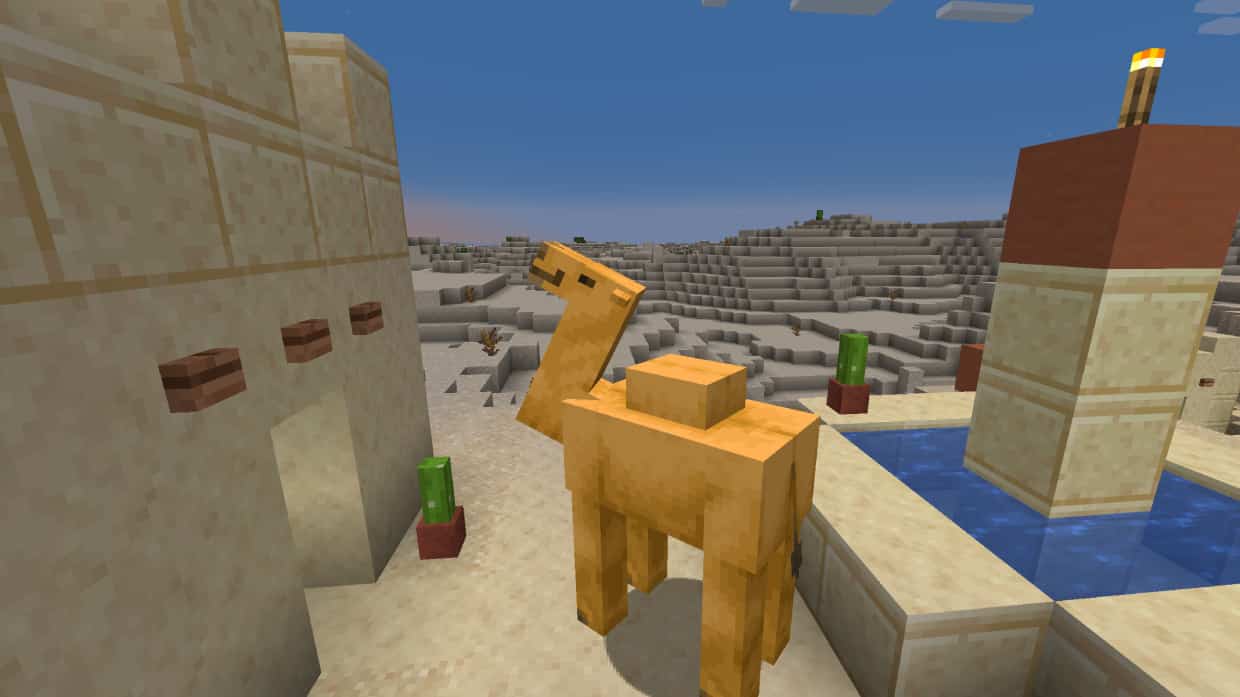 Minecraft camels guide: A camel stands by a fountain in a desert village at sunset.