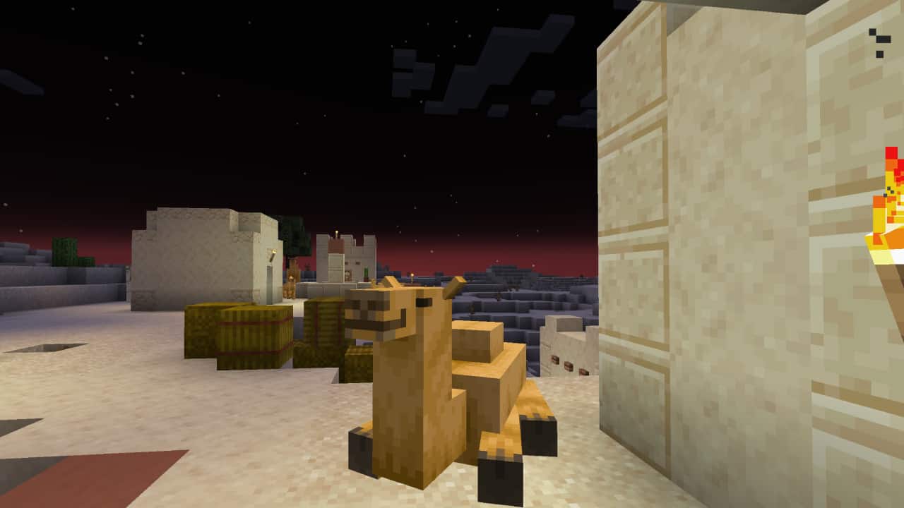 Minecraft camels guide: A camel sits outside a sandstone house in a desert village.