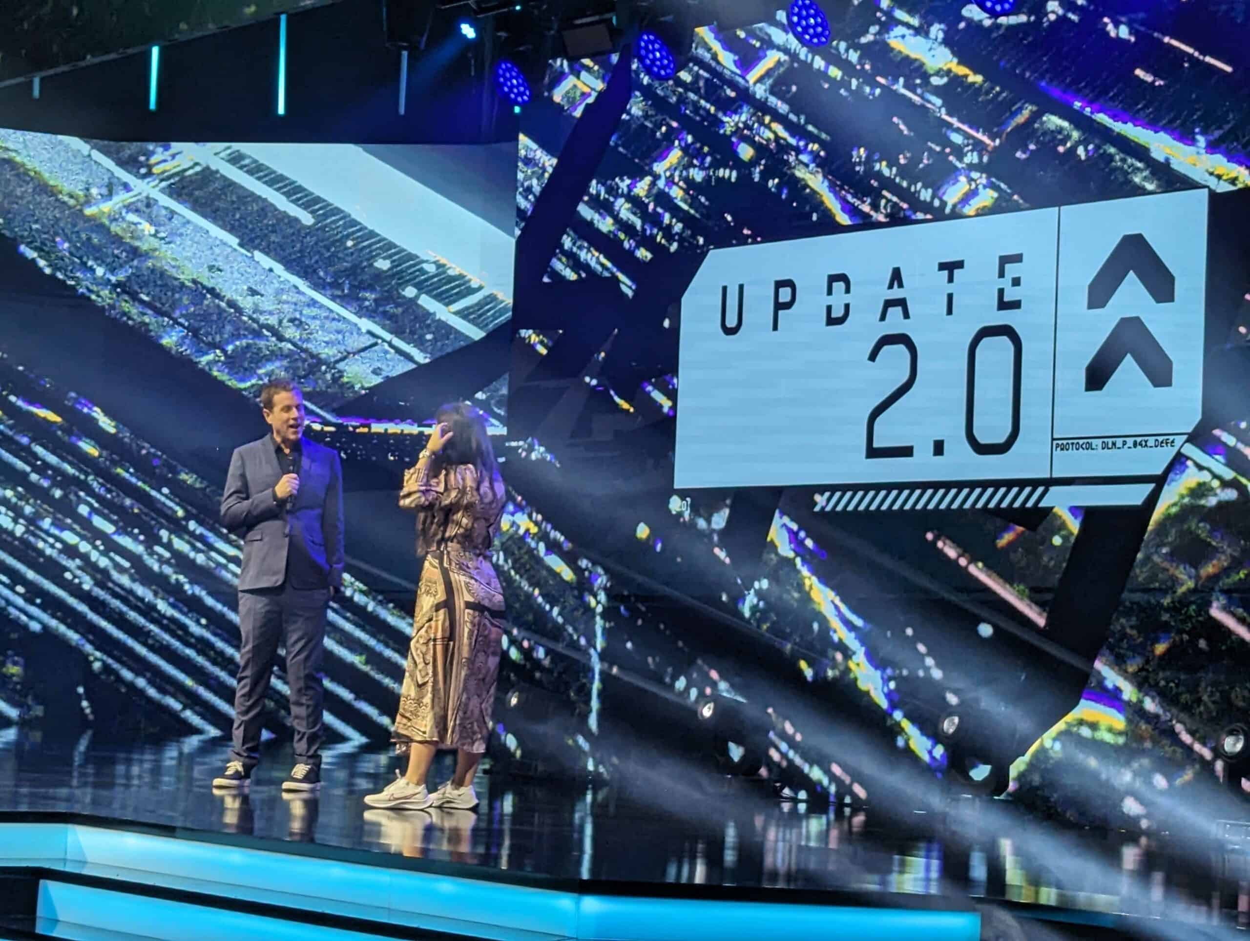 Two people standing on stage announcing the Cyberpunk 2077 2.0 update for current-gen consoles and PC.