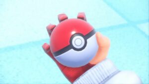 A hand holding a Pokemon ball containing several returning Pokemon from the Indigo Disk.
