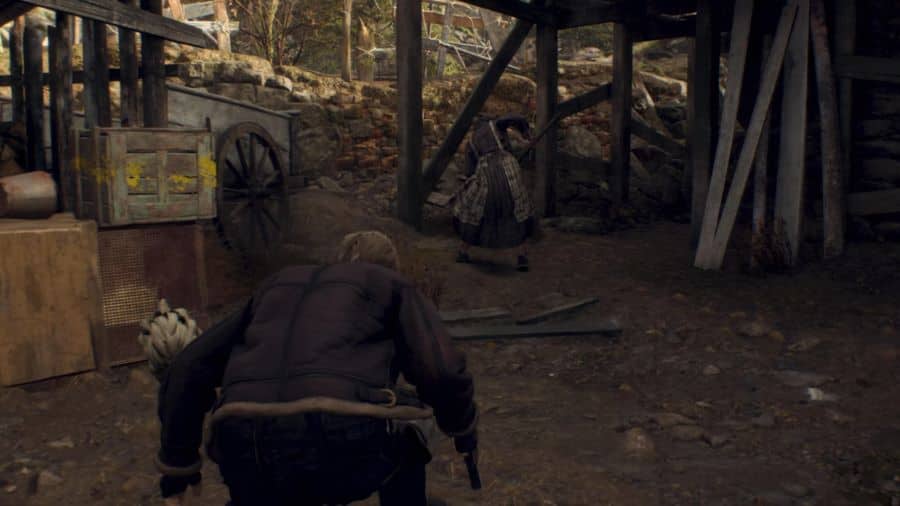 Resident Evil 4 Remake Leon prepares for a stealth kill in the village