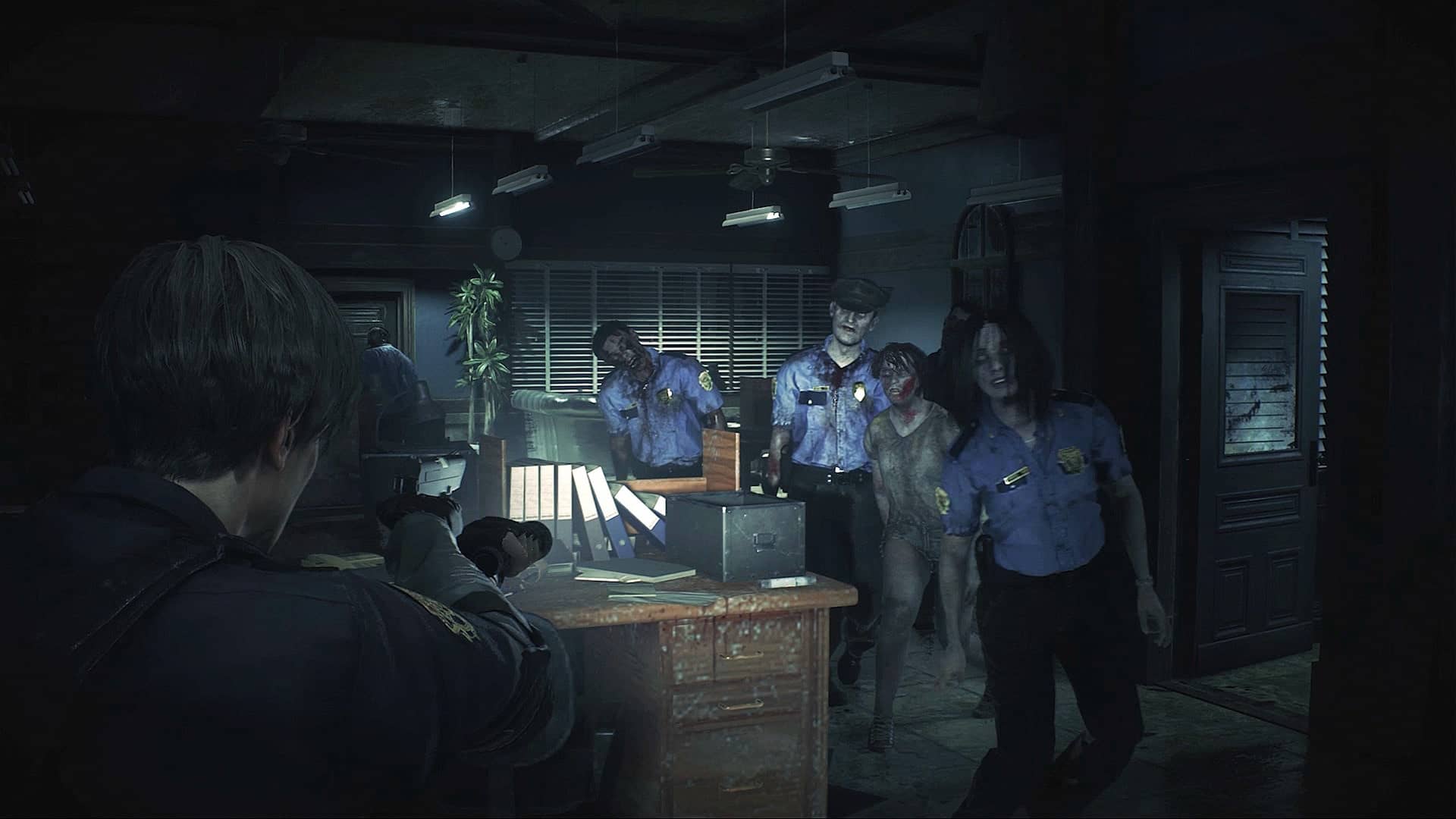 Leon S. Kennedy aims his gun at approaching zombies inside the dimly lit Raccoon Police Department in Resident Evil 2.