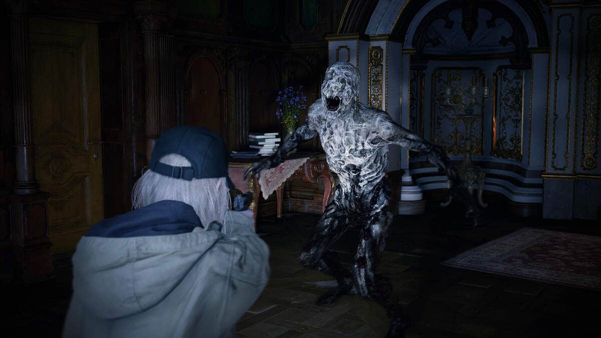 A person in a cap and jacket aims a gun at a monstrous, decaying creature in Resident Evil Village.
