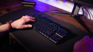 A person is typing on a Steelseries Apex 9 TKL keyboard in front of a monitor.