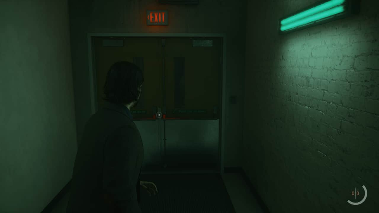 Alan Wake 2 studio door code: In a dimly lit hallway, Alan Wake cautiously stands beneath the glow of a green light.