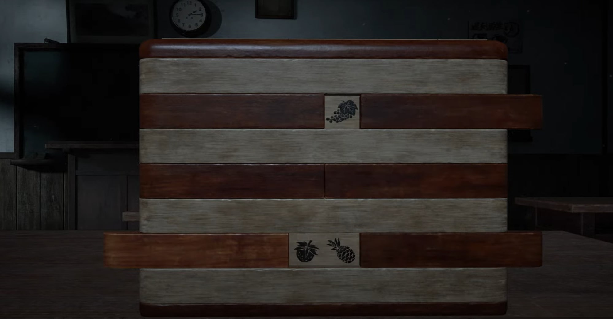 A close-up of a wooden sliding puzzle box with fruit symbols in Silent Hill 2, showing grapes, a strawberry, and a pineapple on engraved tiles.