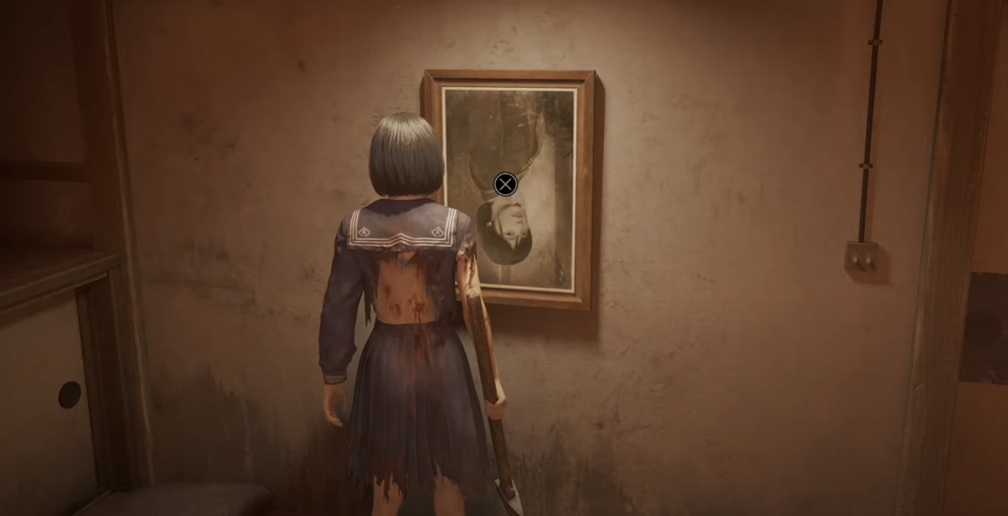 A character in a tattered school uniform examines an upside-down photograph on a wall in Silent Hill 2, standing in a dimly lit, decaying room.