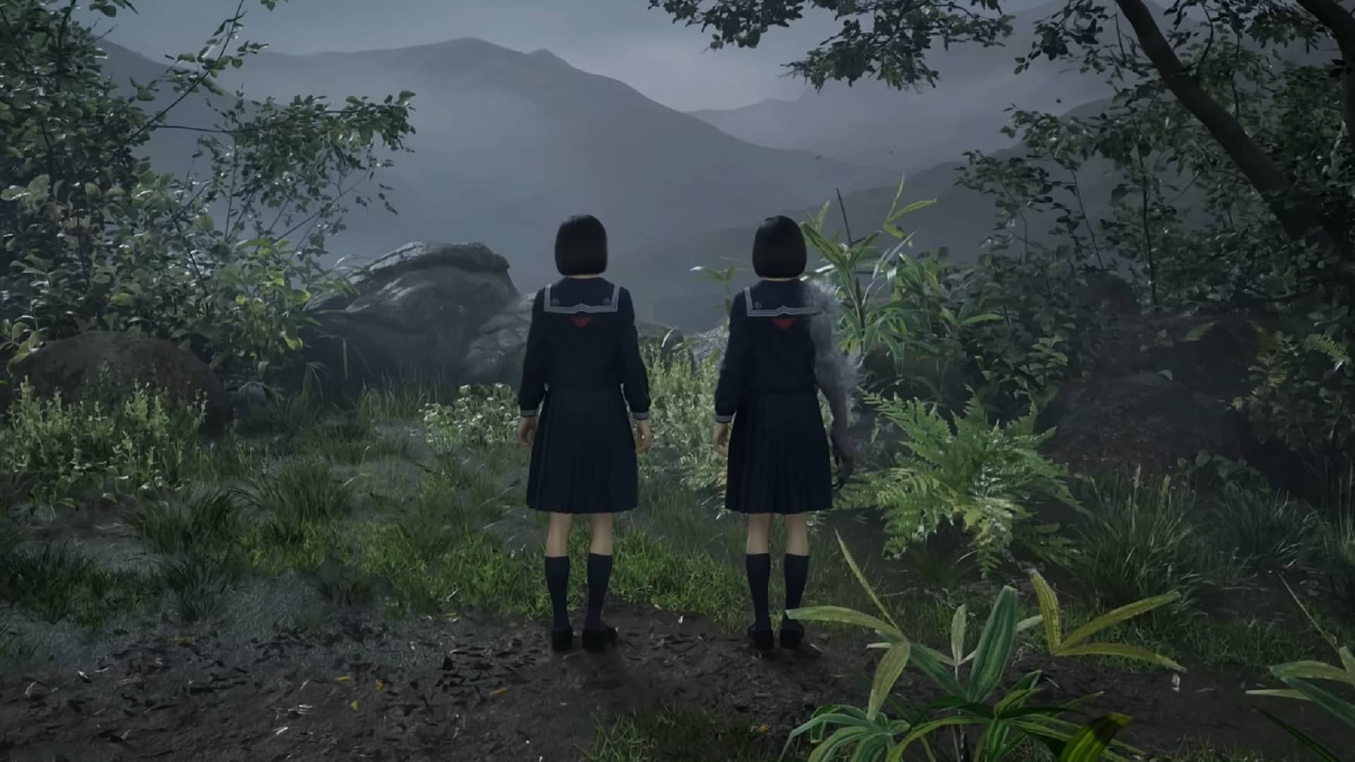 Two schoolgirls stand side by side at the edge of a misty forest in Silent Hill f, gazing toward the fog-covered mountains ahead.