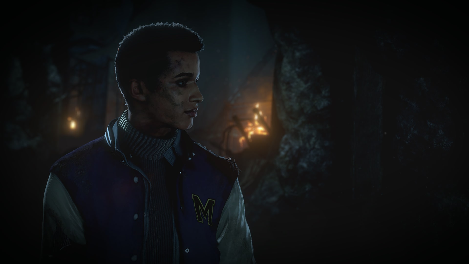Matt from Until Dawn stands in the dimly lit mines, his face dirty and tense as lantern light flickers in the background.