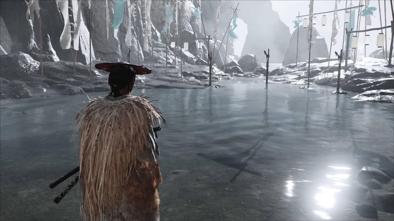 A person in a straw cloak stands by a serene, reflective pool surrounded by rocky terrain in Ghost of Yotei