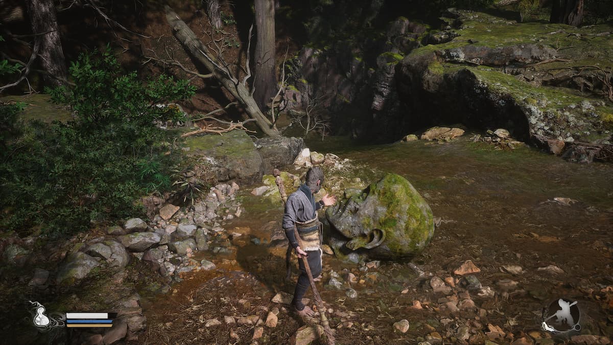 Image of the player character in Black Myth: Wukong, standing over a stone head in the river, holding the Skandha of Form.