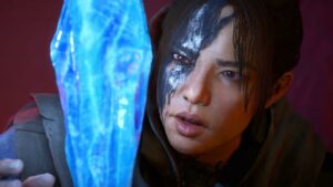 A woman with a black scar looks at a blue crystal