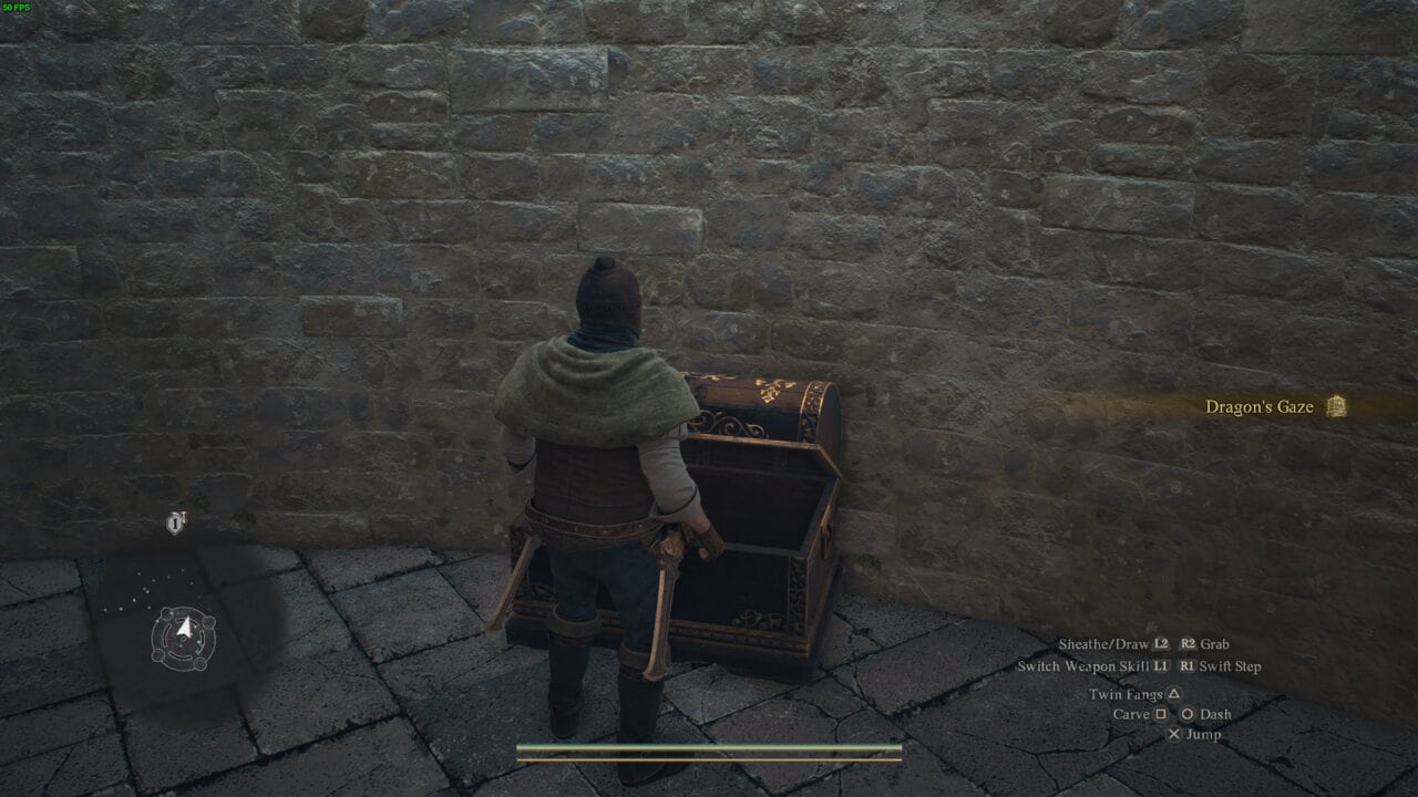 A character in medieval attire standing before an open treasure chest filled with Dragon's Dogma 2 wakestones against a stone wall.