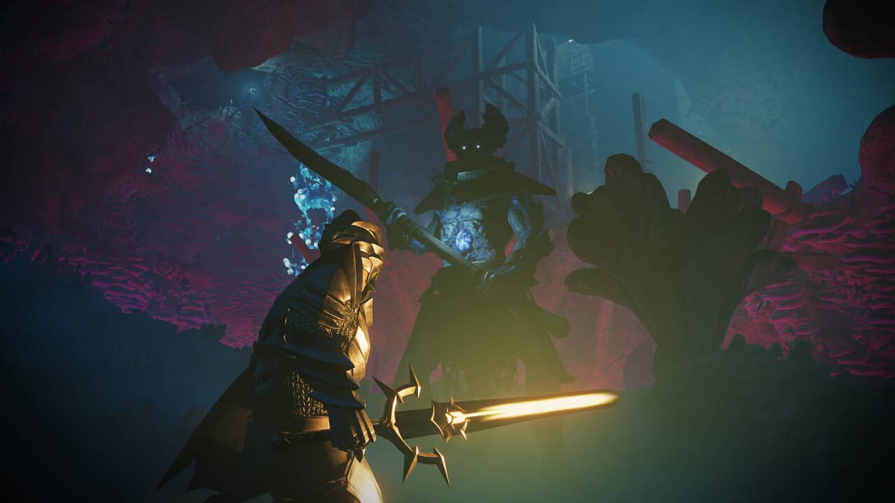 A man is holding a sword in front of an enshrouded cave.