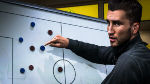 FC 25 developers on Career Mode, Football Manager, FIFA revival: Nuri Sahin pointing at a magnet on a white tactics board.