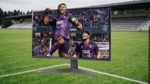 FM25 player animations a game changer: Two footballers celebrating inside a PC monitor on a football pitch.