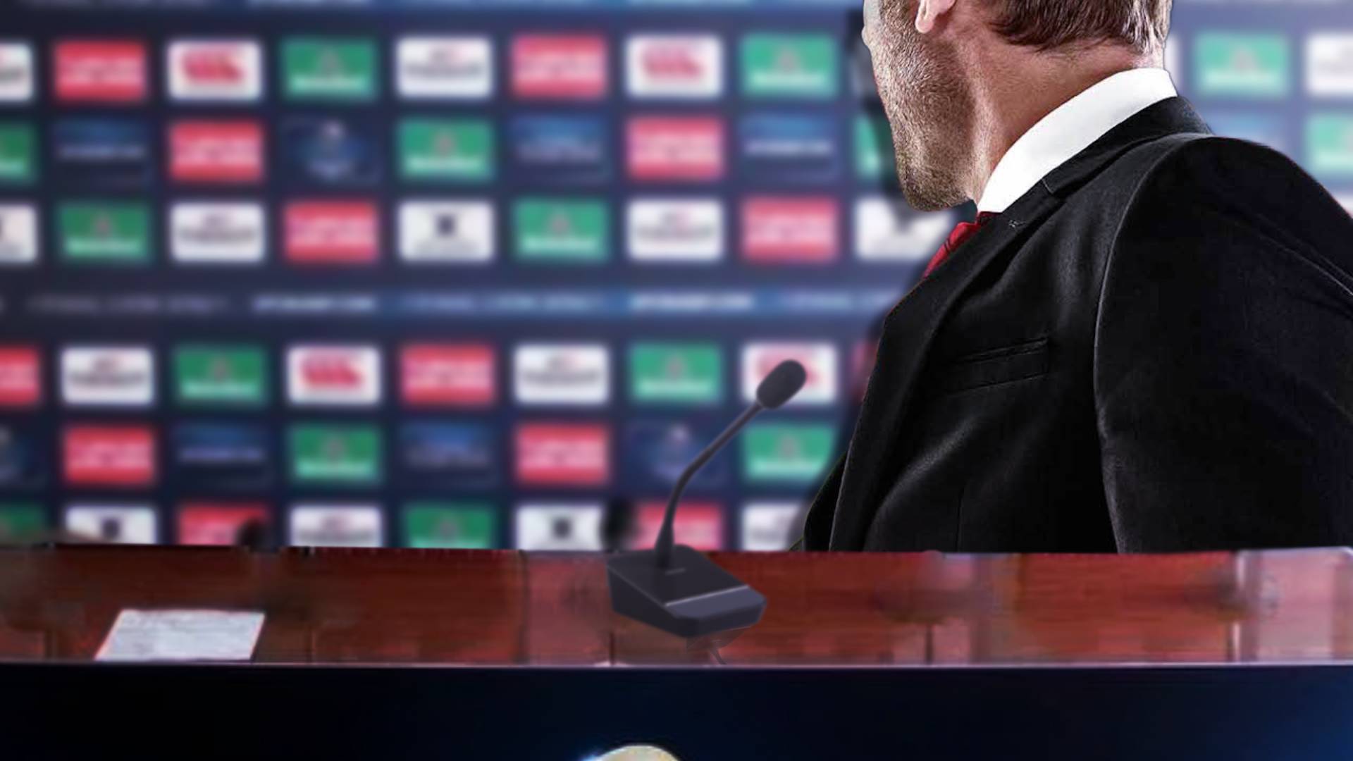 A Football Manager at a press conference looking at the wall