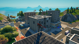 Fortnite Creative how to get to Main Island: A player with an Alan Wake skin standing on a roof overlooking Tilted Towers in Fortnite Creative.